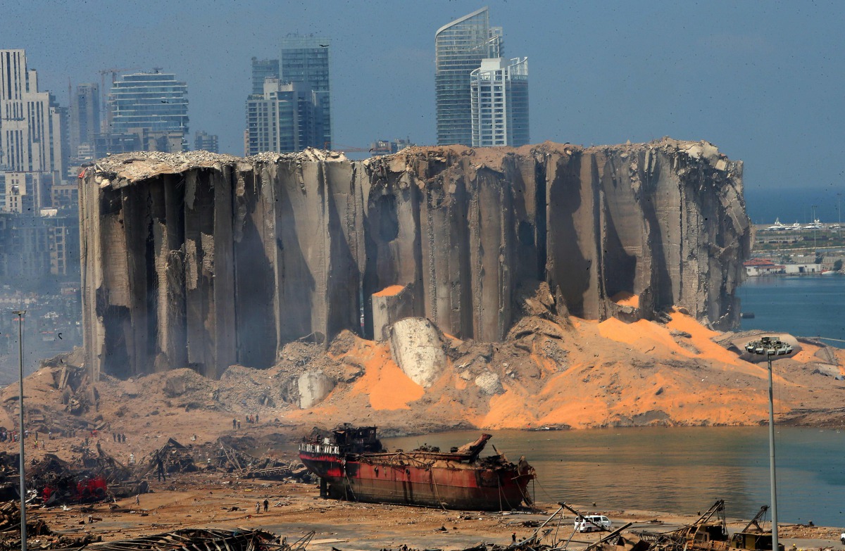 TOPSHOT - A picture taken on August 5, 2020 shows the damaged grain silo and a burnt boat at Beirut's harbour, one day after a powerful twin explosion tore through Lebanon's capital, resulting from the ignition of a huge depot of ammonium nitrate at the c