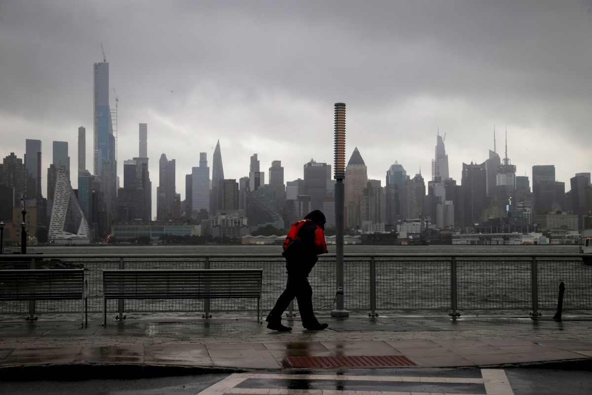 A man walks into heavy wind and rain along the waterfront of the Hudson River in front of the New York City skyline during Tropical Storm Isaias in Weehawken, New Jersey, U.S., August 4, 2020. REUTERS/Mike Segar TPX IMAGES OF THE DAY
