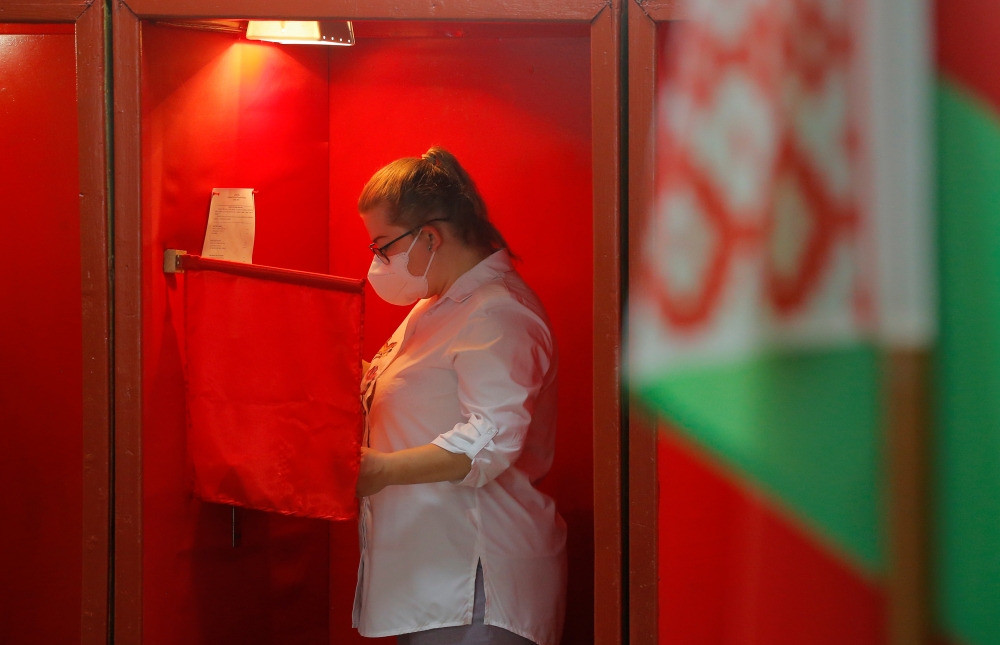 A woman wearing a protective face mask stands inside a voting booth at a polling station during the presidential election in Minsk, Belarus August 9, 2020. REUTERS/Vasily Fedosenko