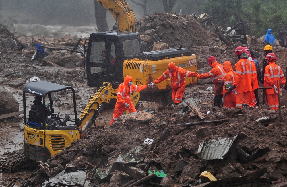 Rescue workers look for survivors at the site of a landslide during heavy rains in Idukki.
