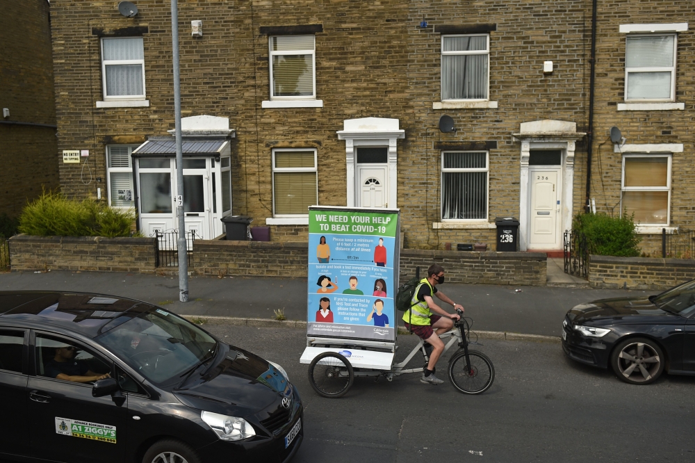 In a promotion funded by Calderdale Council, Phil Mearns rides his ad bike displaying advice on how to slow the spread of the coronavirus through the streets of Halifax in northern England on August 9, 2020, as local lockdown restrictions are reimposed du