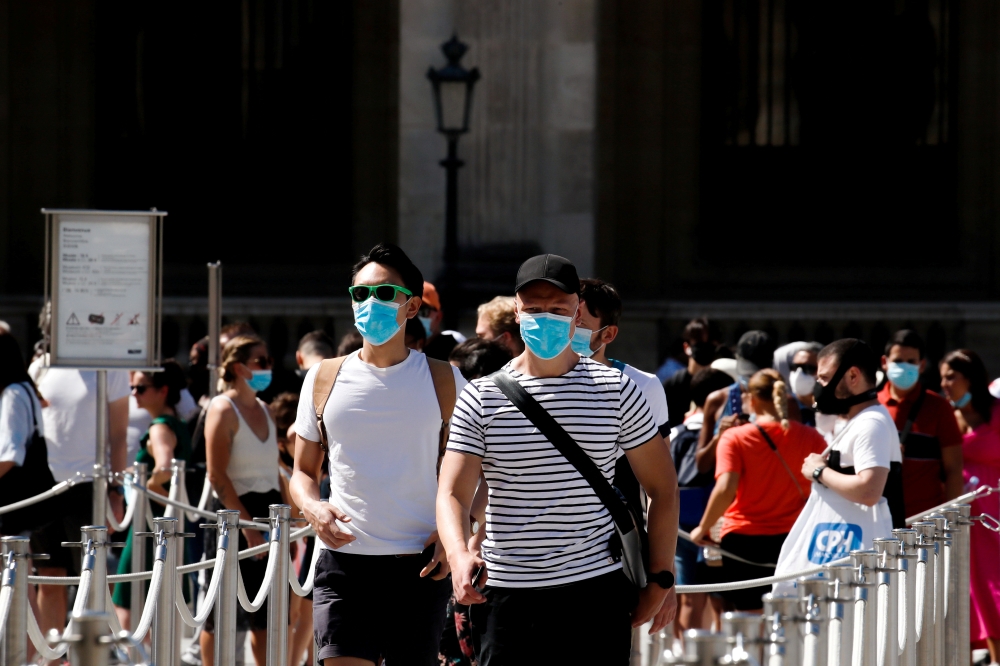 People wearing protective masks walk near the Louvre Museum as France reinforces mask-wearing as part of efforts to curb a resurgence of the coronavirus disease (COVID-19) across the country, in Paris, France August 6, 2020. REUTERS/Gonzalo Fuentes/File P