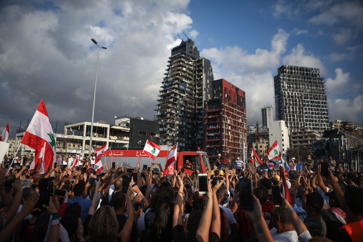 A crowd cheers members of the Lebanese Civil Defence during a commemoration ceremony for the victims of the Beirut port explosion across from the capital's harbour, on August 11, 2020. / AFP / PATRICK BAZ
