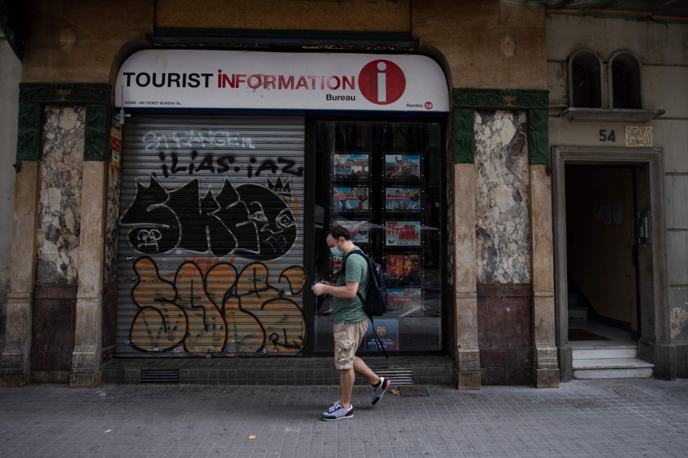 A man walks past a closed tourist office in the centre of Barcelona on August 12, 2020. / AFP / Josep LAGO