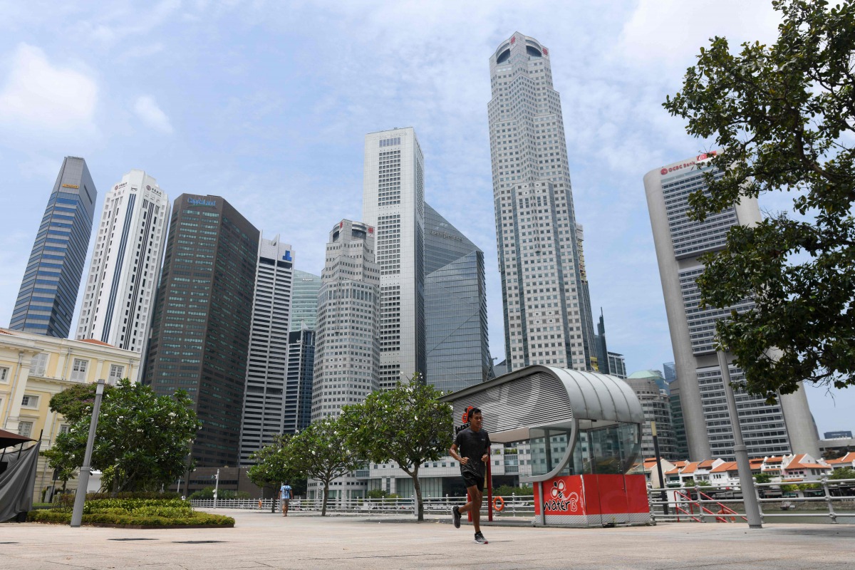 A man jogs along the Singapore River, as the financial business district is seen in the background, in Singapore on August 11, 2020. / AFP / Roslan RAHMAN
