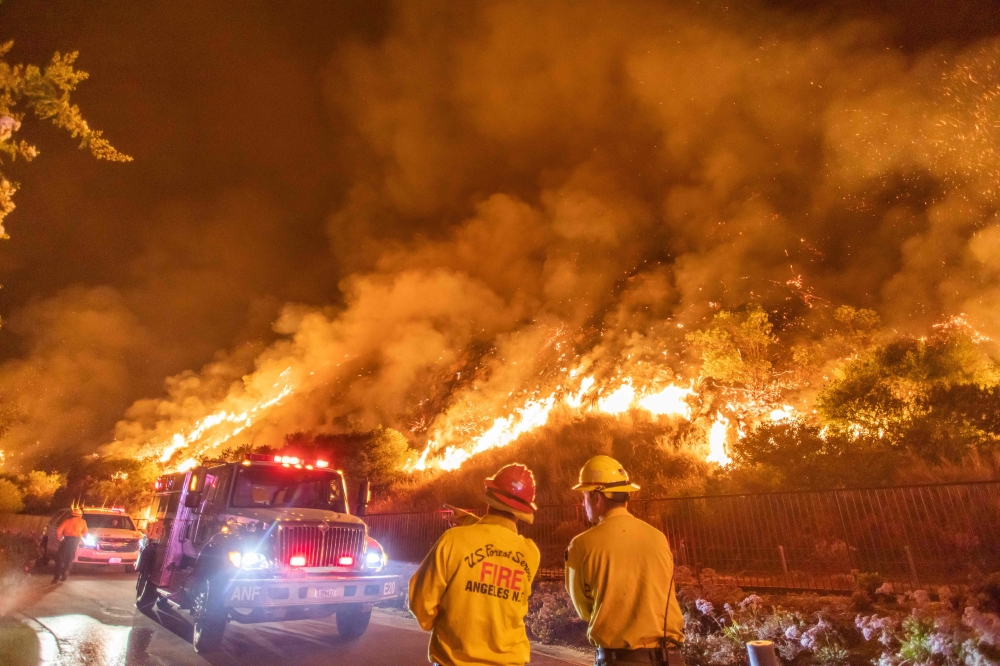 Firefighters battle the smoke and flames from the Ranch Fire in the hills in Azusa, California, on August 14, 2020, 25 miles (40kms) east of Los Angeles. The Los Angeles County Fire Department was alerted to the brush fire at 2:45 pm. By August 13 in the 