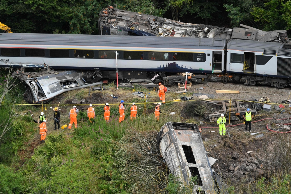 Members of the emergency services inspect the debris and derailed carriages at the scene of the train crash near Stonehaven in northeast Scotland on August 12, 2020. / AFP / POOL / Ben BIRCHALL