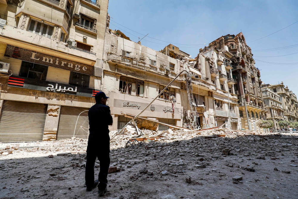 A policeman stands by the rubble at the scene of a building collapse along Kasr el-Nile street in the Egyptian capital Cairo's downtown district, on August 15, 2020. / AFP / Khaled DESOUKI
