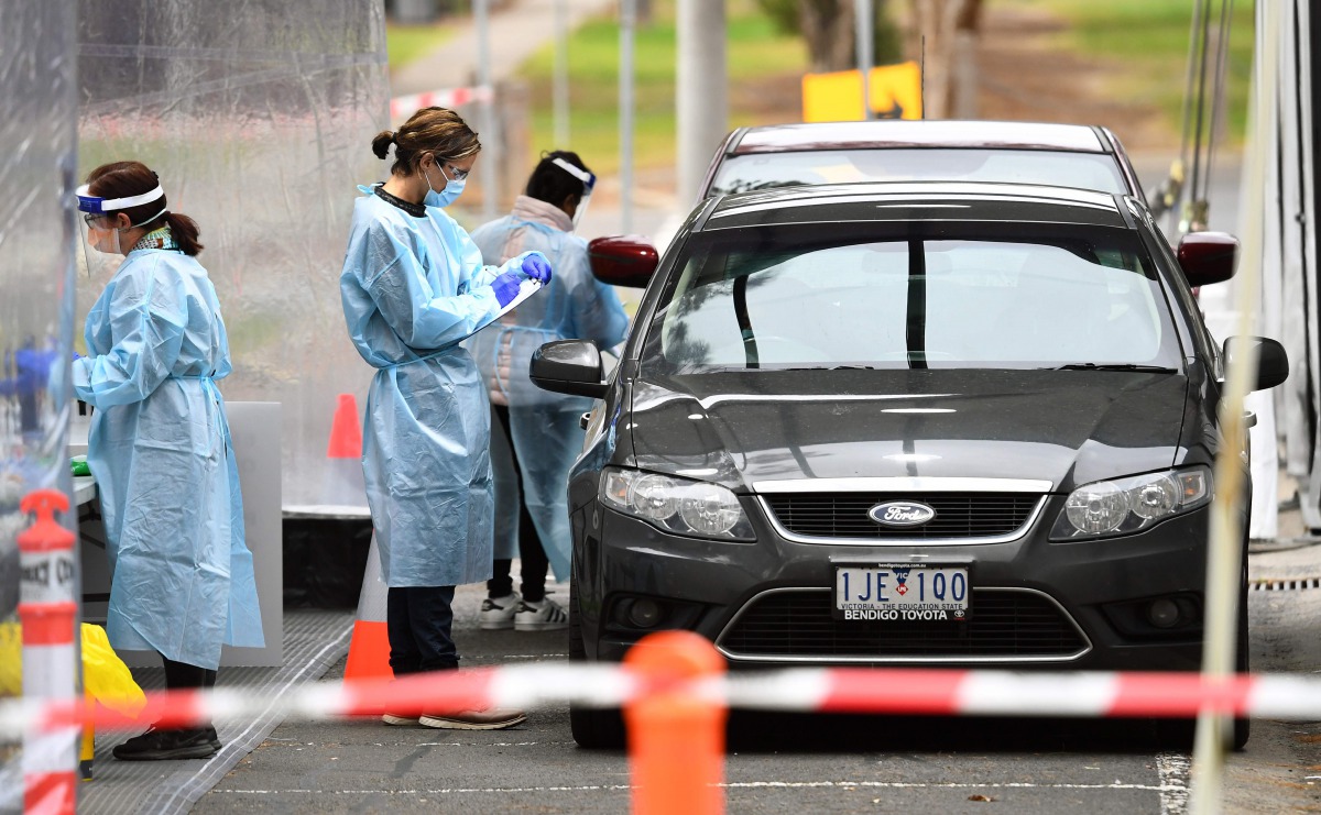 Medical staff prepare to take a swab at a drive-through testing clinic in Melbourne on August 13, 2020. Australia's virus-hit Victoria state reported a major drop in new coronavirus cases on August 13, but officials warned against complacency amid a 