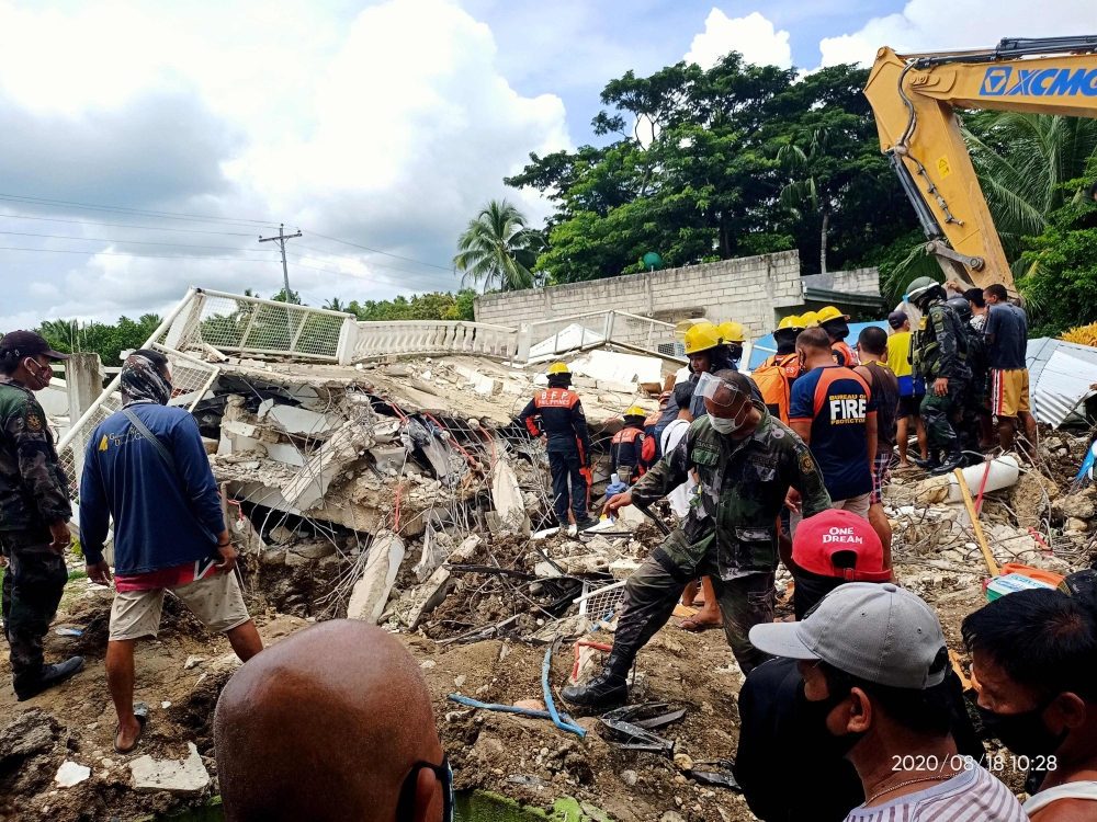 This handout photo received on August 18, 2020 from the Facebook page of Javee Vallecer shows rescuers looking for survivors at the site of a damaged house after a 6.6-magnitude earthquake hit the town of Cataingan in the central Philippine province of Ma