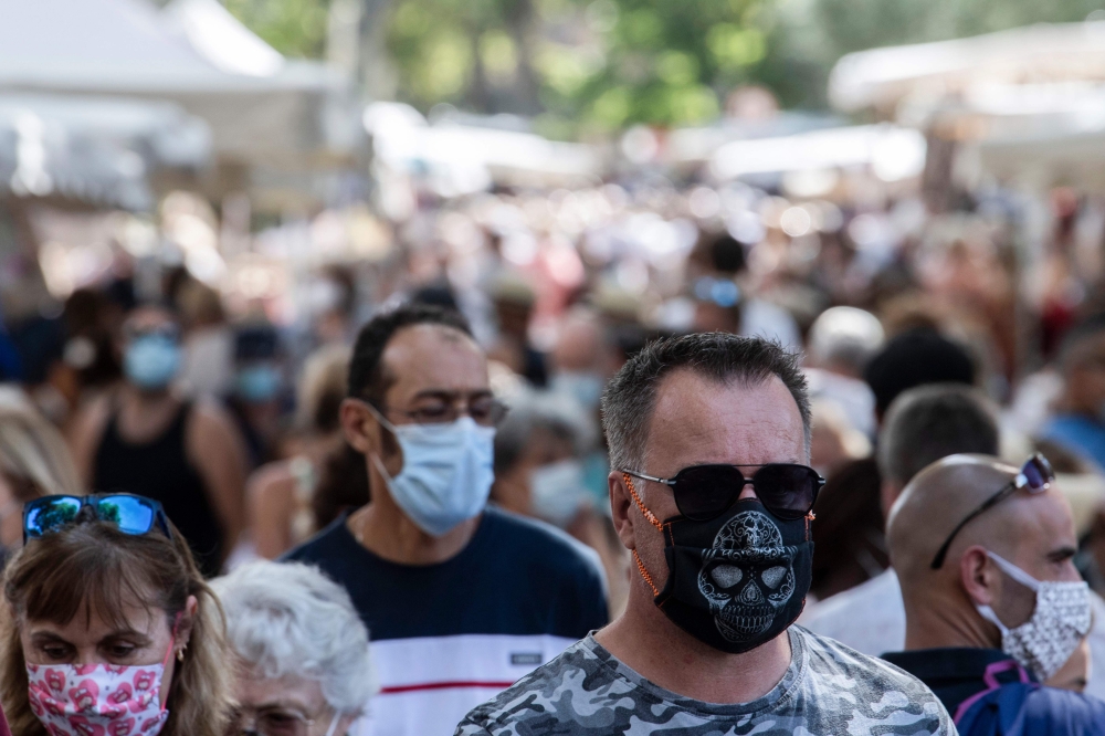 Pedestrians wear face masks as they walk in a congested street market of Lourges, southern France on August 18, 2020. / AFP / Christophe SIMON