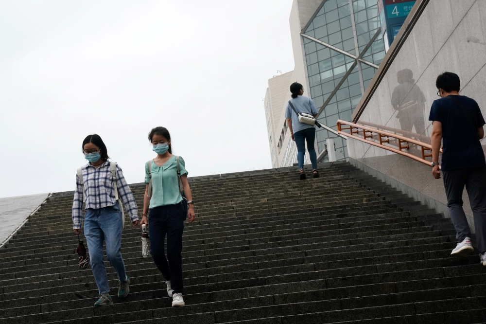 People wearing face masks walk down steps near a subway station, following the coronavirus disease (COVID-19) outbreak, in Beijing, China August 18, 2020. REUTERS/Tingshu Wang