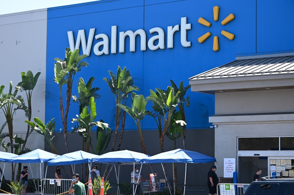 In this file photo taken on July 22, 2020 people wearing face coverings wait in line to shop at Walmart, in Burbank, California.  / AFP / Robyn Beck
