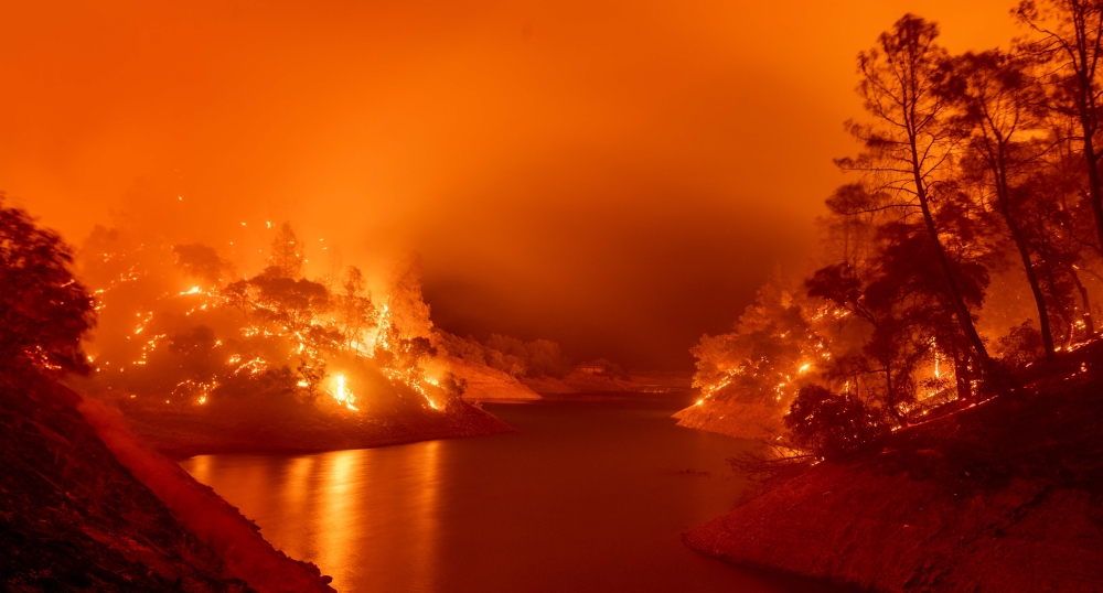 In this long exposure photograph, flames consumes both sides of a segment of Lake Berryessa during the Hennessey fire in the Spanish Flat area of Napa, California on August 18, 2020.  / AFP / JOSH EDELSON