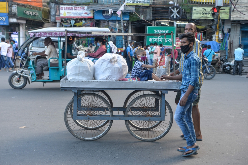 A man and his son push a cart where a young boy sits in Siliguri on August 19, 2020, as a state-imposed lockdown will be held on August 20 and 21 against the surge in COVID-19 coronavirus cases. / AFP / DIPTENDU DUTTA