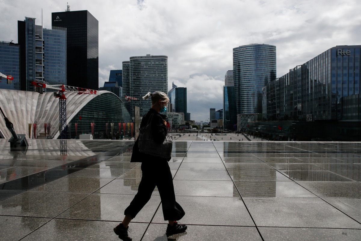 A woman wearing a protective mask walks at the financial and business district of La Defense as France reinforces mask-wearing in public places as part of efforts to curb a resurgence of the coronavirus disease (COVID-19) across the country, near Paris, F