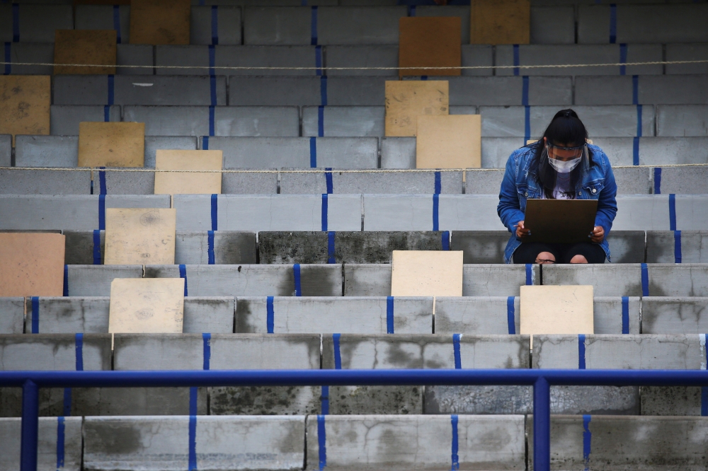 A woman wearing a protective face mask and a face shield holds social distancing as a measure to contain the spread of the coronavirus disease (COVID-19) before taking the entrance exam for Mexico's National Autonomous University in the stands of Universi