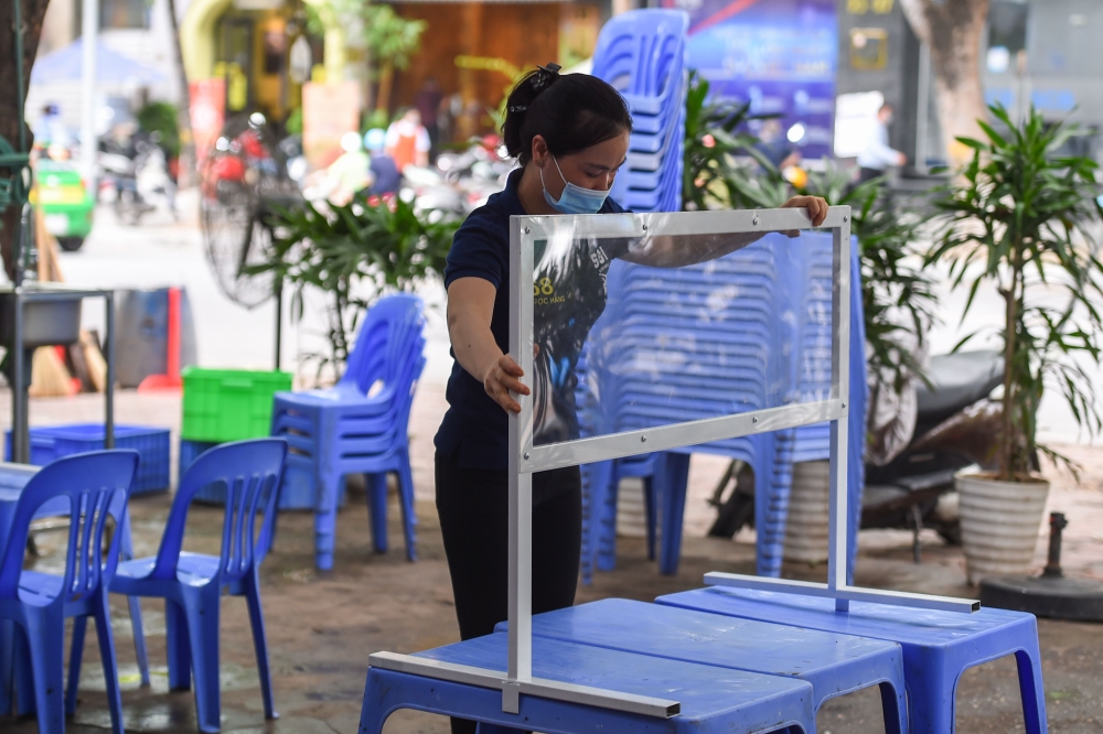 A worker sets up a plastic partition, used as a preventive measure against the spread of the COVID-19 novel coronavirus, at a bia hoi in Hanoi on August 20, 2020. / AFP / Nhac NGUYEN