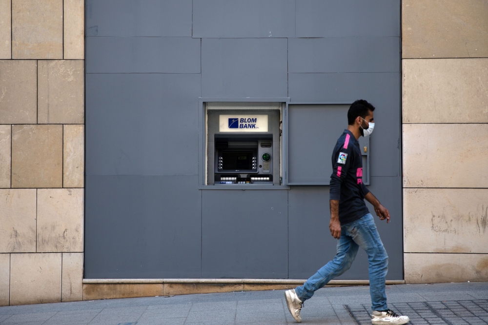 A man wearing a face mask walks past a fortified Blom Bank ATM machine, as Lebanon imposed a partial lockdown for two weeks starting on Friday in an effort to counter the spread of the coronavirus disease (COVID-19), in Beirut, Lebanon August 21, 2020. RE
