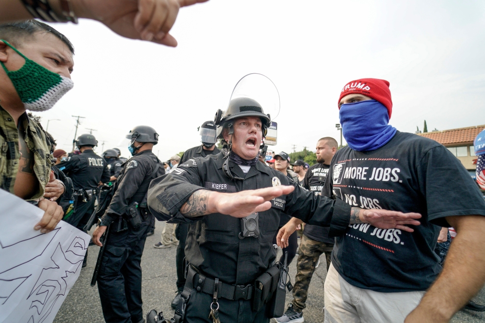 A Los Angeles police officer attempts to stop a confrontation between Trump supporters (R) and counter-protestors during a pro-Trump rally in Tujunga, 25 miles north of Los Angeles (40km), California, August 21, 2020. / AFP / Kyle Grillot