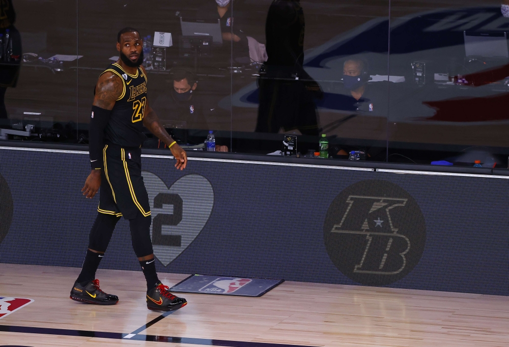 LeBron James #23 of the Los Angeles Lakers walks along the sideline with Kobe Bryant signage in Game Four of the Western Conference First Round against the Portland Trail Blazers during the 2020 NBA Playoffs at AdventHealth Arena at ESPN Wide World Of Spo