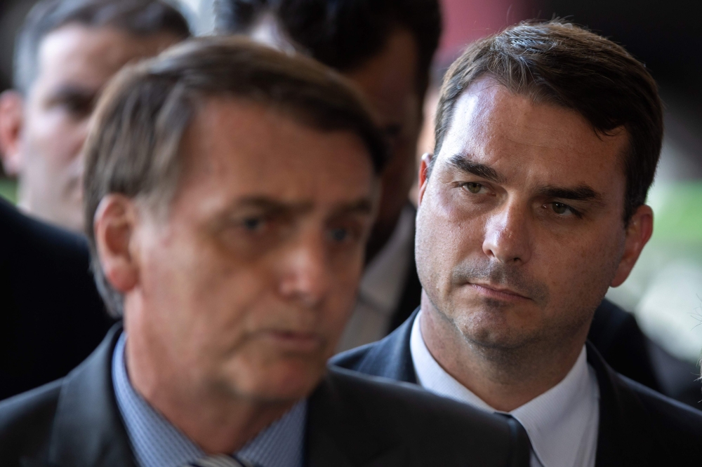 In this file photo taken on November 28, 2018, the president-elect of Brazil, Jair Bolsonaro (L) and his son Flavio Bolsonaro (R), arrive for a press conference on the appointment of the ministers of Citizenship, Tourism and Regional Development at the he