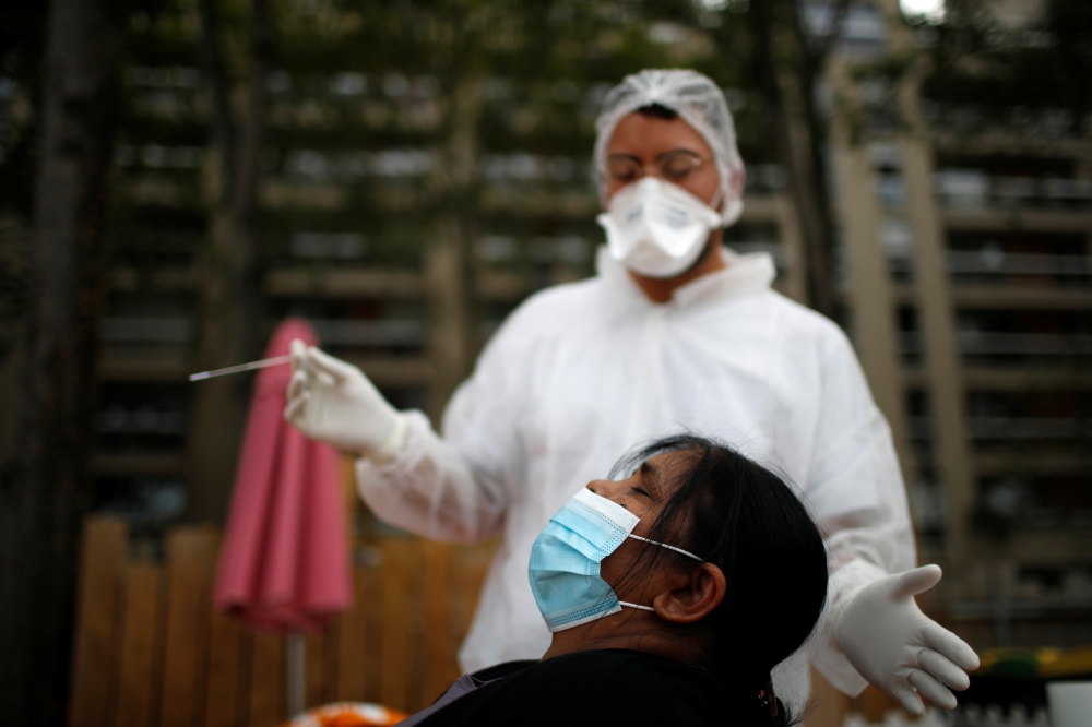 :A health worker, wearing a protective suit and a face mask, prepares to administer a nasal swab to a patient at a testing site for the coronavirus disease (COVID-19) installed at the Bassin de la Villette in Paris, France, August 25, 2020. REUTERS/Gonzal