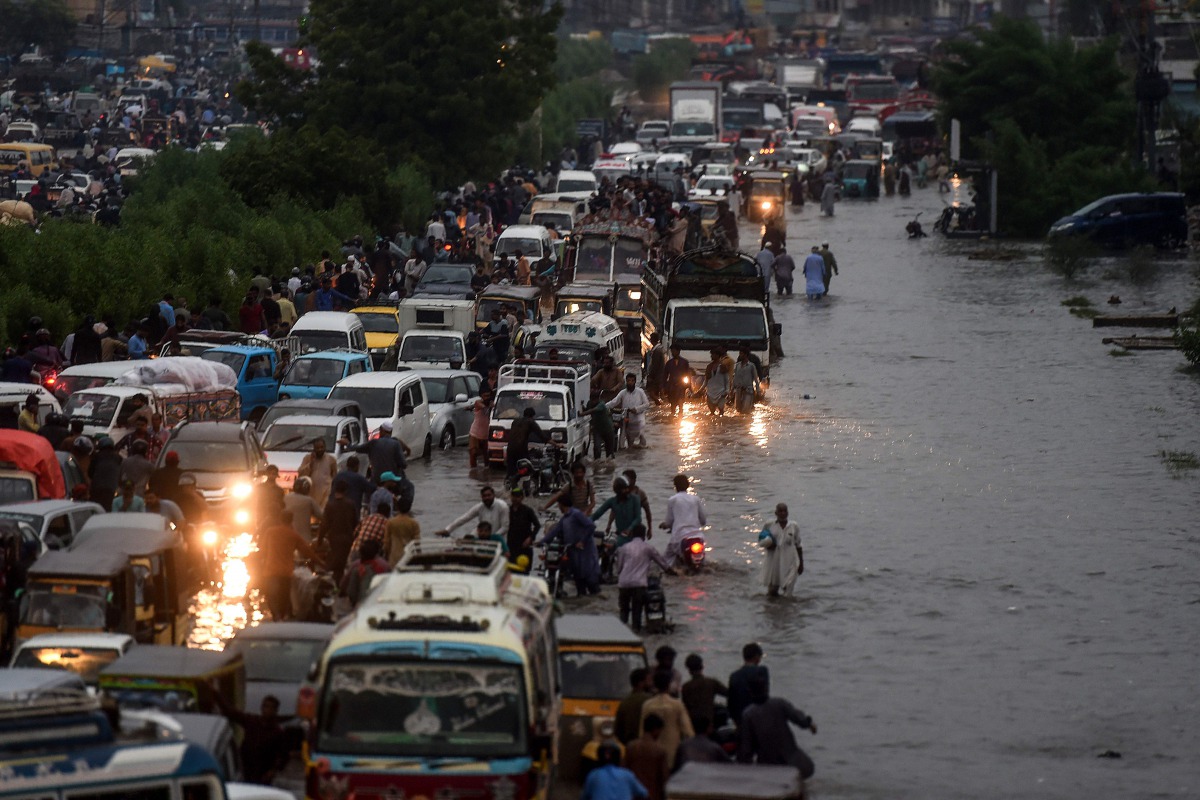 Motorists and pedestrians wade through a flooded street after heavy monsoon rains in the Pakistan's port city of Karachi on August 21, 2020. / AFP / Asif HASSAN
