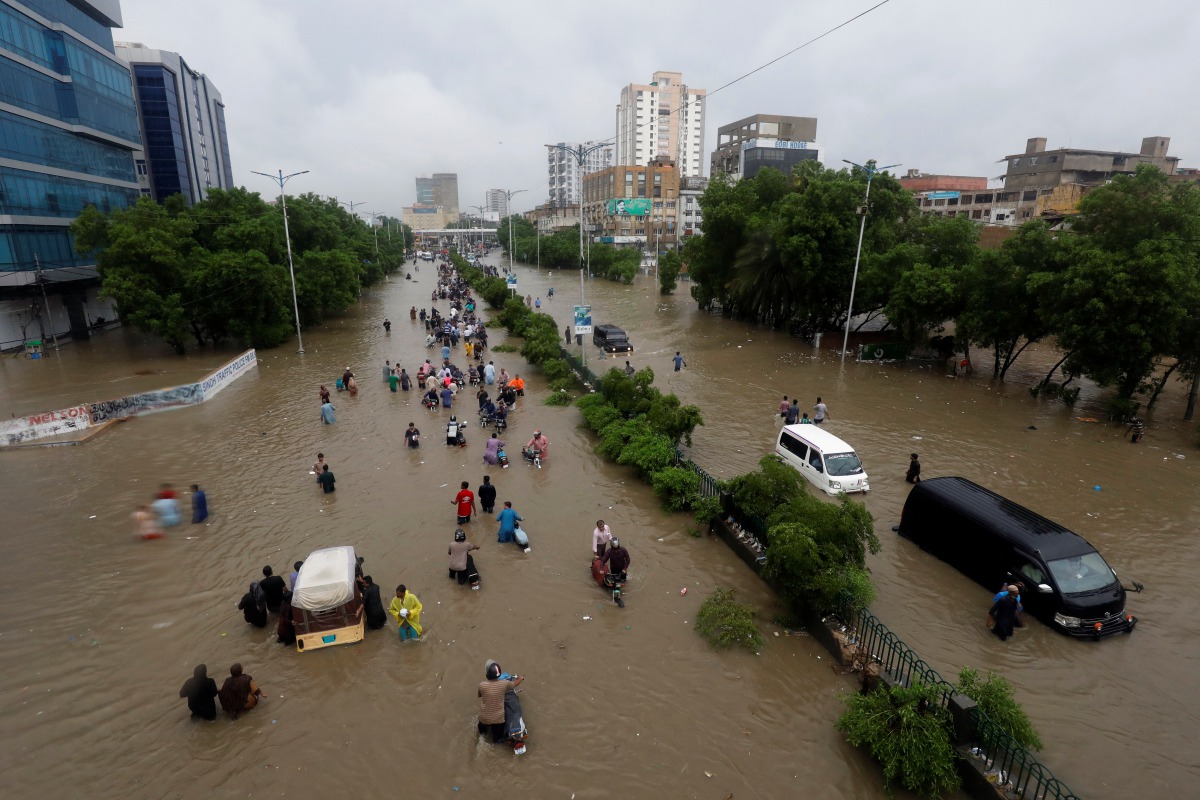 People wade through the flooded road with submerged vehicles during monsoon rain, as the outbreak of the coronavirus disease (COVID-19) continues, in Karachi, Pakistan August 27, 2020. REUTERS/Akhtar Soomro
