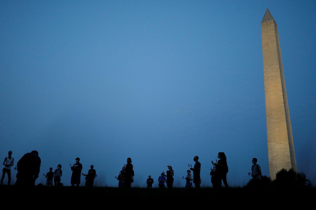 Activists stand with American flags at sunrise to memorialize victims of the coronavirus disease (COVID-19) outbreak, near the Washington Monument in Washington, U.S., August 27, 2020. REUTERS/Tom Brenner
