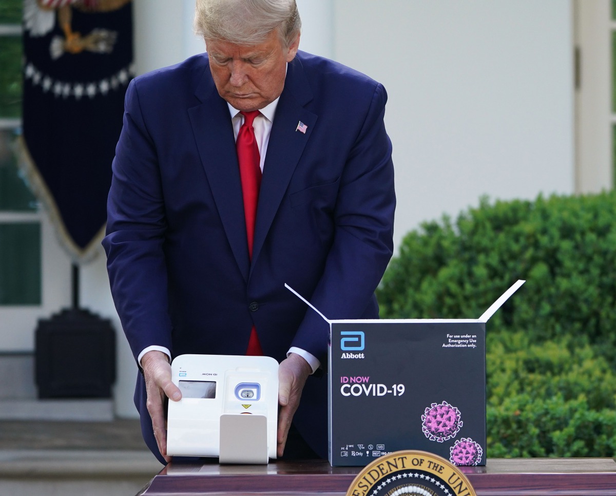 (FILES) In this file photo taken on March 30, 2020, US President Donald Trump holds a 5-minute test for Covid-19 from Abbott Laboratories during the daily briefing on the coronavirus pandemic, in the Rose Garden of the White House in Washington, DC. Trump