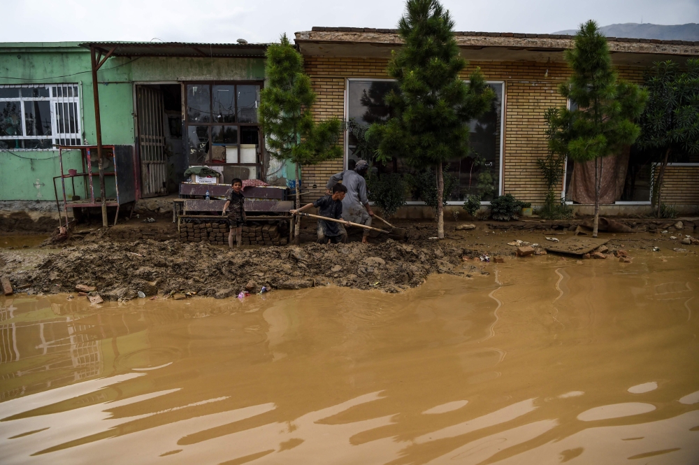 Villagers use shovels to clear the mud on the roadside after flash floods ffected the area at Sayrah-e-Hopiyan in Charikar, Parwan province on August 27, 2020.  AFP / WAKIL KOHSAR