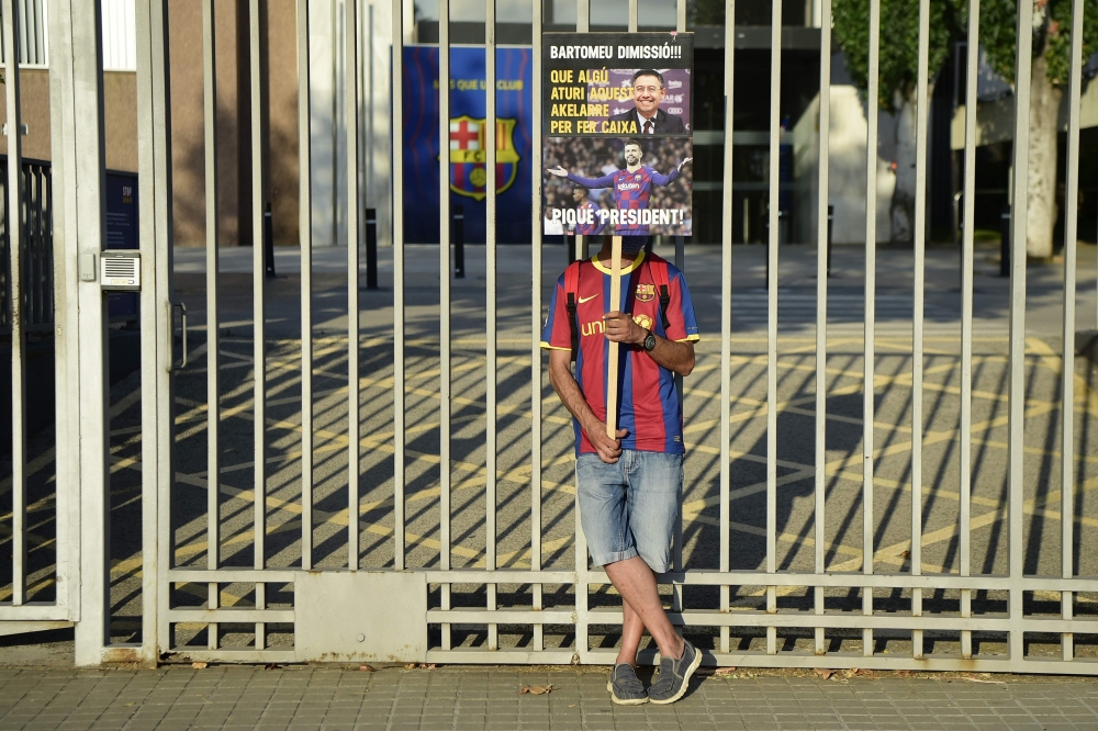 An FC Barcelona fan holds a placard calling for the resignation of club president Josep Maria Bartomeu and replacing him with Barcelona's Spanish defender Gerard Pique as fans gather outside the Camp Nou stadium in Barcelona on August 27, 2020 after Barce