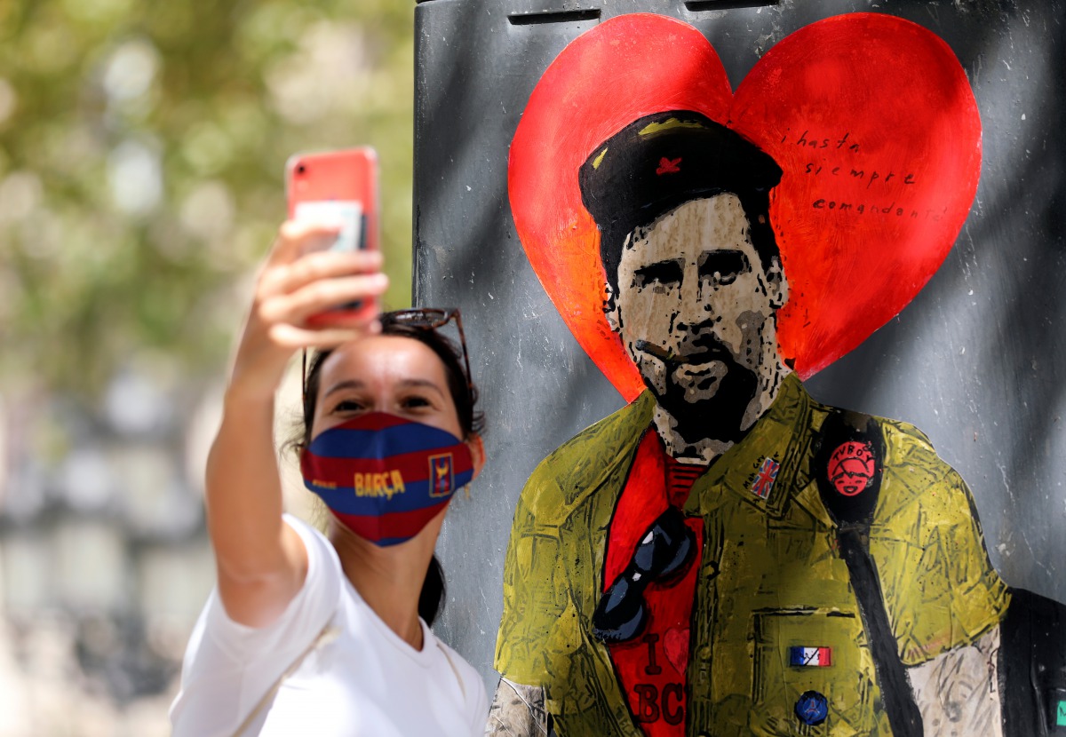 A woman takes a selfie with a mural of Lionel Messi dressed as Che Guevara as FC Barcelona's squad arrive for coronavirus disease (COVID-19) test, ahead of the resumption of training on August 31, in Barcelona, Spain August 30, 2020. REUTERS/Nacho Doce
