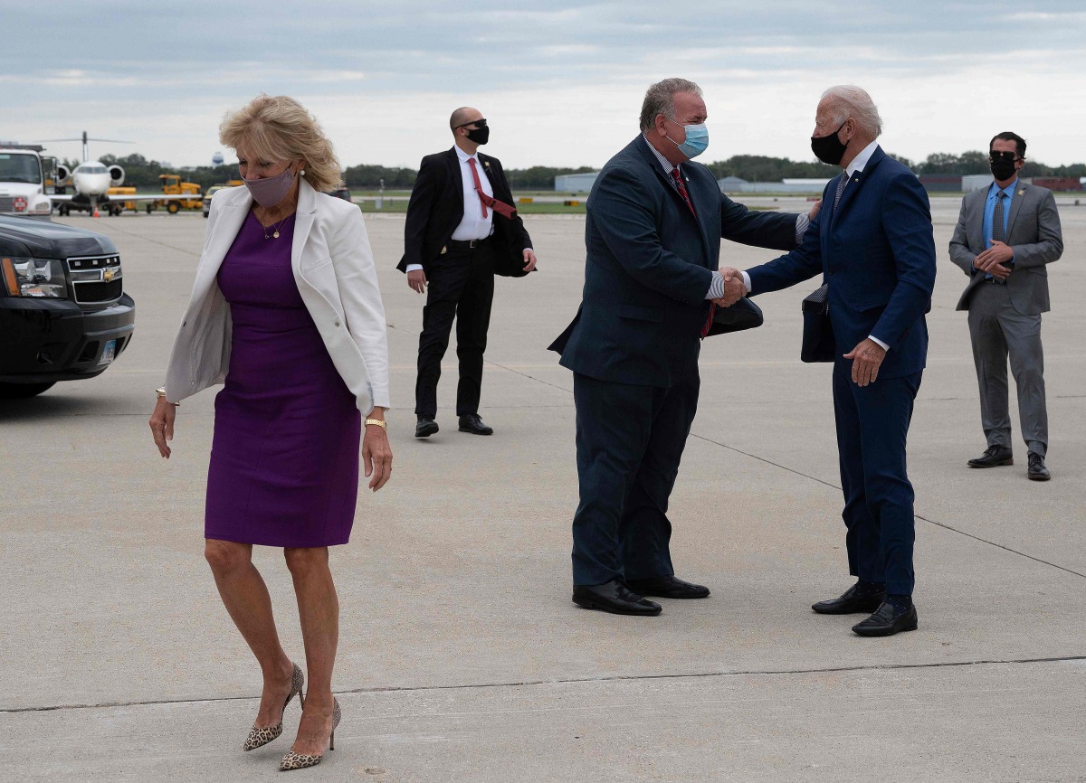 Democratic presidential candidate Joe Biden , with his wife Dr. Jill Biden (L), is greeted by US Senator Scott Fitzgerald as he arrives at Milwaukee Mitchell International Airport, in Milwaukee, Wisconsin, on September 3, 2020. / AFP / JIM WATSON

