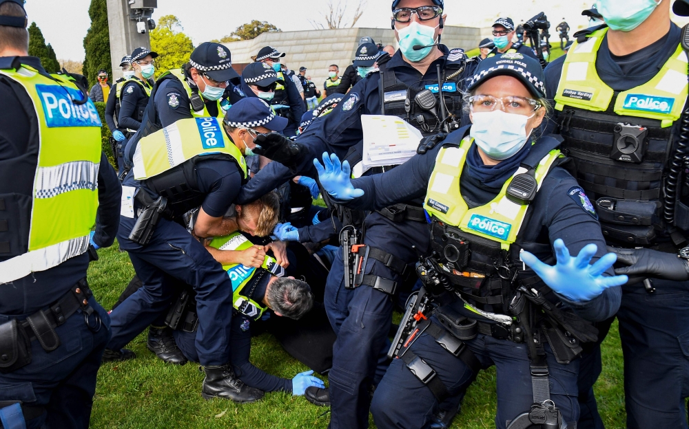 Police tackle protesters in Melbourne on September 5, 2020 during an anti-lockdown rally protesting the state's strict lockdown laws as a preventive measure against the COVID-19 coronavirus. / AFP / William West 
