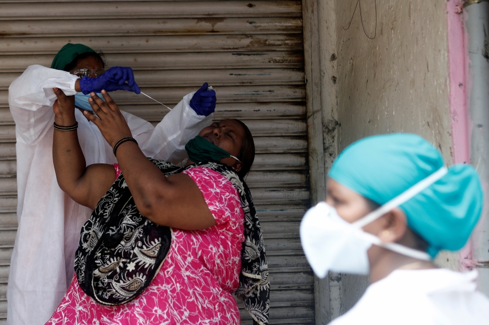 A woman reacts as a health worker in personal protective equipment (PPE) takes a swab during a check-up campaign for the coronavirus disease (COVID-19) in a slum area in Mumbai, India September 5, 2020. REUTERS/Francis Mascarenhas