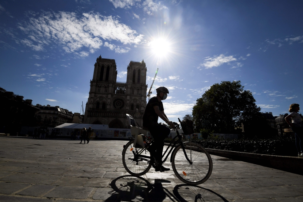 :A man rides his bicycle by Notre-Dame cathedral, on September 4, 2020, in Paris. / AFP / ALAIN JOCARD
