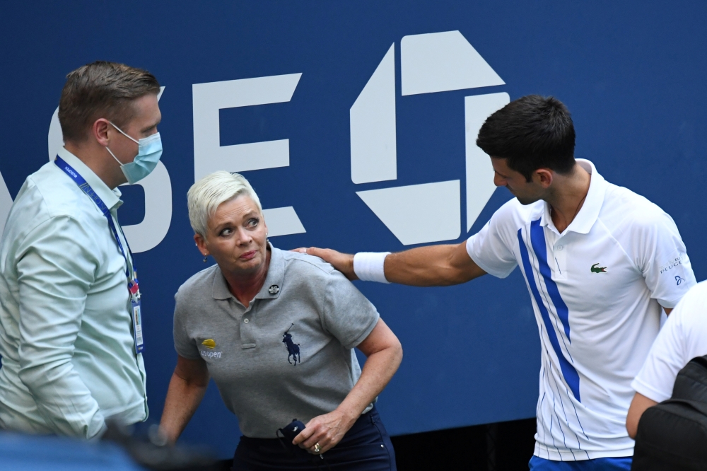 Novak Djokovic of Serbia and a tournament official tend to a linesperson who was struck with a ball by Djokovic against Pablo Carreno Busta of Spain (not pictured) on day seven of the 2020 U.S. Open tennis tournament at USTA Billie Jean King National Tenn