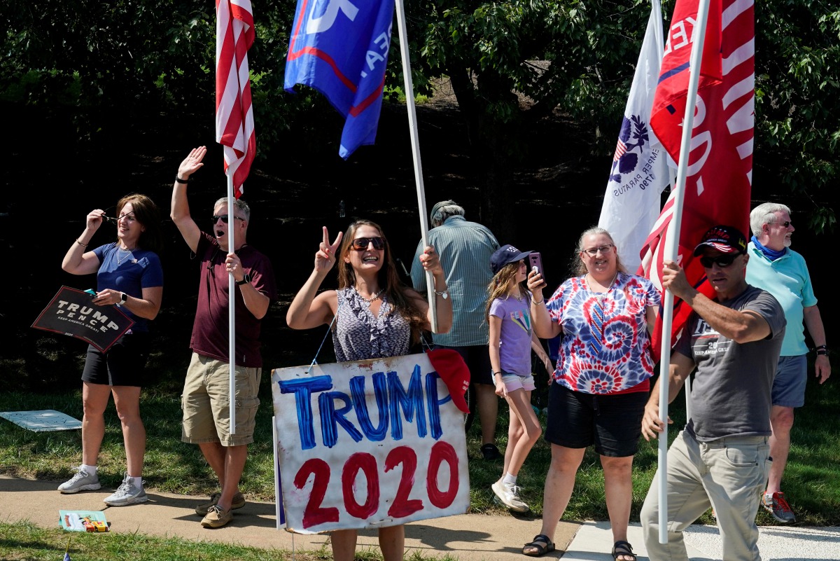 FILE PHOTO: Trump supporters wave flags as the motorcade carrying U.S. President Donald Trump departs from the Trump National Golf Club in Sterling, Virginia, U.S., September 6, 2020. REUTERS/Joshua Roberts/File Photo
