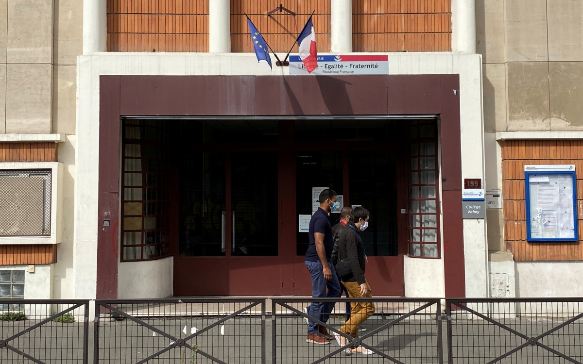 People wearing protective face masks walk past the College Valmy school in Paris, France, September 10, 2020. REUTERS/Rali Benallou

