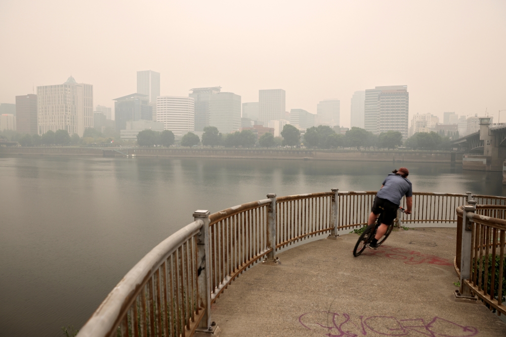 A man rides a bike as smoke from wildfires covers an area near Portland, Oregon, U.S., September 11, 2020. REUTERS/Carlos Barria