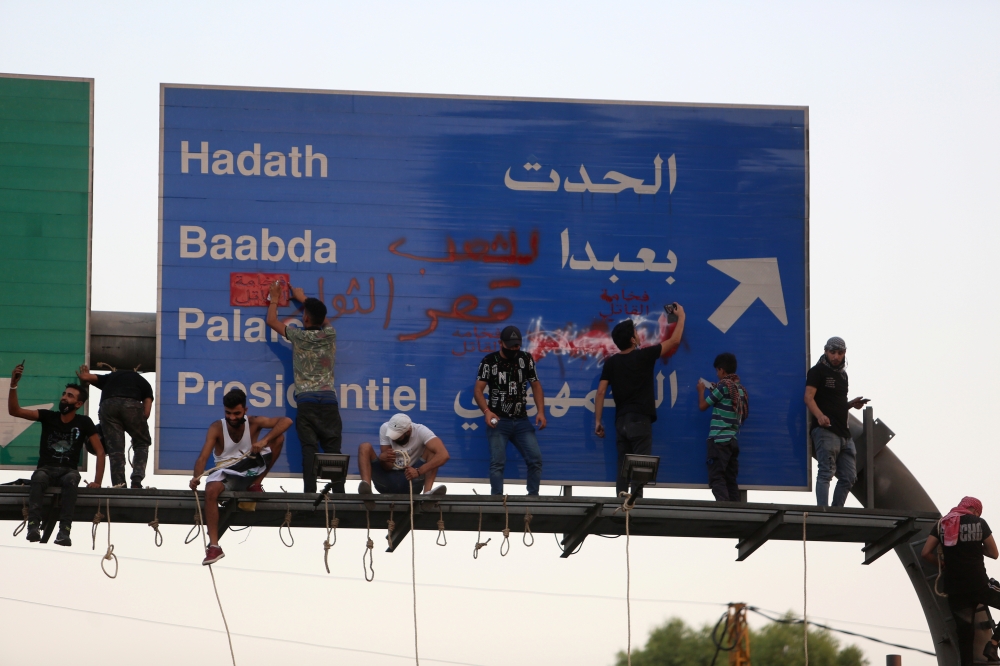 Demonstrators write on a road sign during anti-government protests near presidential palace in Baabda, Lebanon September 12, 2020. REUTERS/Aziz Taher