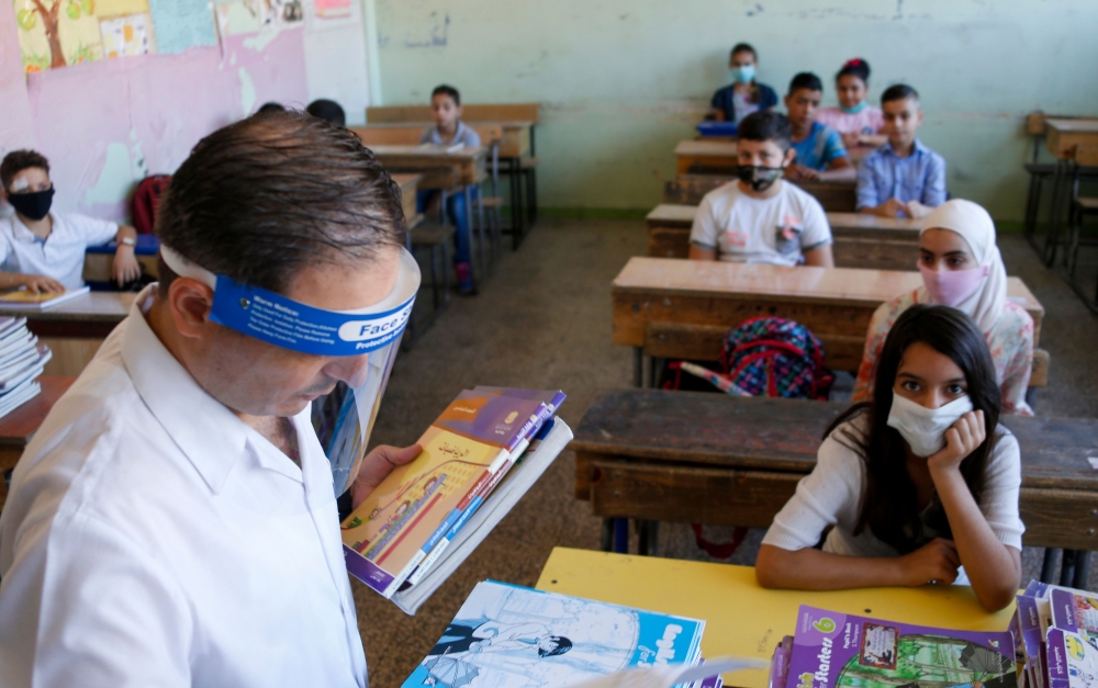 Syrian pupils, some wearing protective face masks, take their seats in class in the capital Damascus on September 13, 2020, during the first day of the school year. / AFP / LOUAI BESHARA