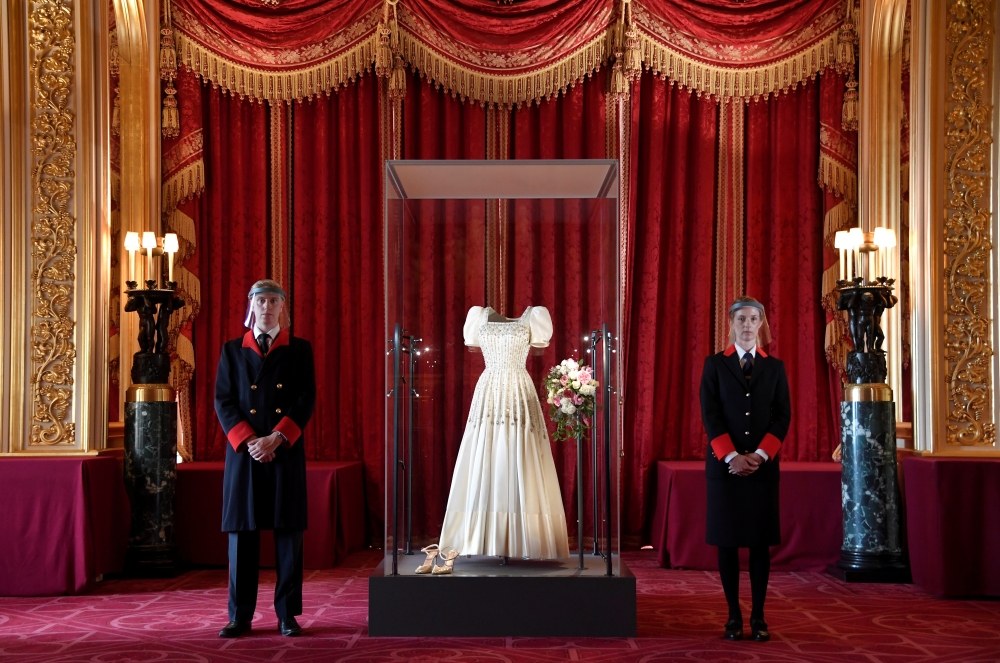 Two Windsor Castle wardens view the wedding dress worn by Princess Beatrice of York at her July 2020 wedding, which was originally worn by Britain's Queen Elizabeth in the 1960s, ahead of it going on public display at Windsor Castle, Windsor, Britain, Sep