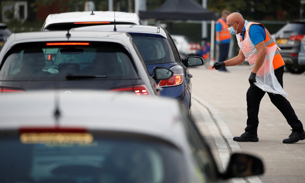 An NHS track and trace worker talks with people as they arrive at a drive in test centre following the outbreak of the coronavirus disease (COVID-19) in Bolton, Britain, September 22, 2020. REUTERS/Phil Noble