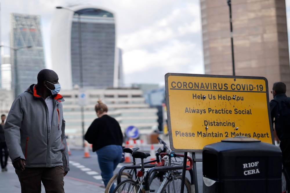 A pedestrian wears a facemask due to the novel coronavirus COVID-19 pandemic on London Bridge in central London on September 25, 2020. Britain's Prime Minister Boris Johnson, this week announced a host of new restrictions, including early closing times fo