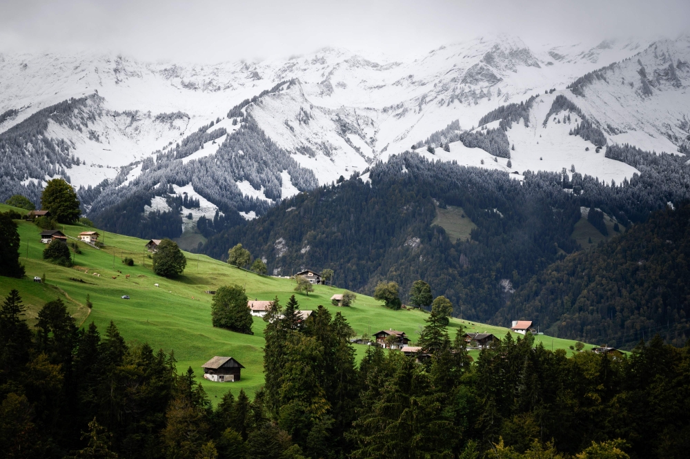 This photograph taken on September 26, 2020 shows chalets near fresh snow in Kiental, Bernese Oberland as cold winds and a sharp drop in temperatures have brought the first signs of winter to the Swiss Alps. / AFP / Fabrice COFFRINI