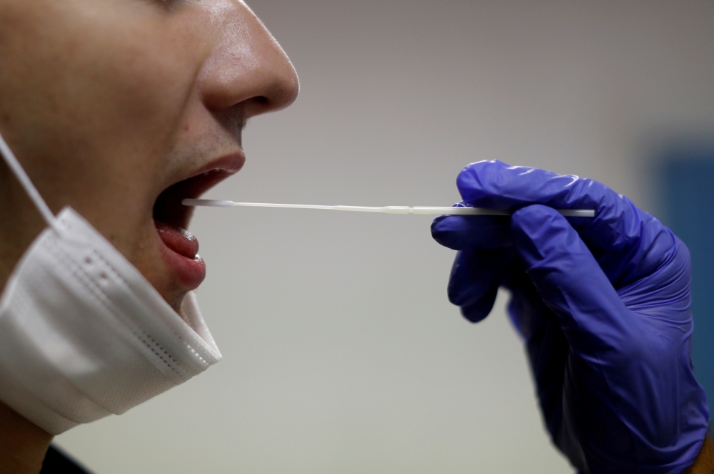 FILE PHOTO: A firefighter from the Marins-Pompiers of Marseille (Marseille Naval Fire Battalion) takes a saliva sample from a colleague who is being tested for the coronavirus disease (COVID-19) at their fire station in Marseille, France, September 22, 20