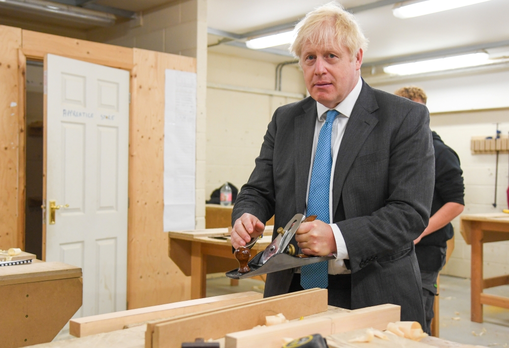 British Prime Minister Boris Johnson tries his hand at woodwork as he visists Exeter College in Exeter, Britain September 29, 2020. Finnbarr Webster/Pool via REUTERS